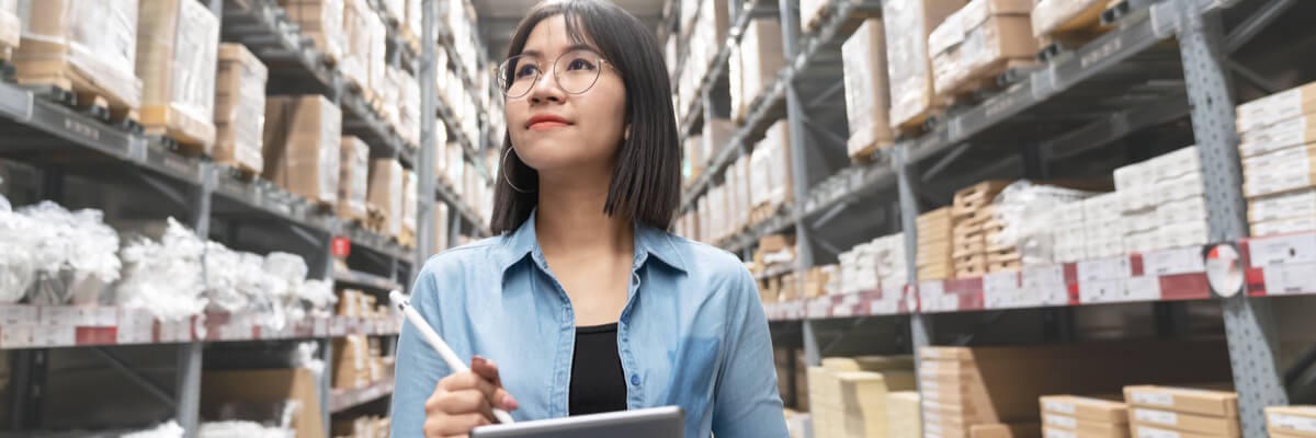 Young  woman  looking up stocktaking inventory in warehouse store by computer tablet 