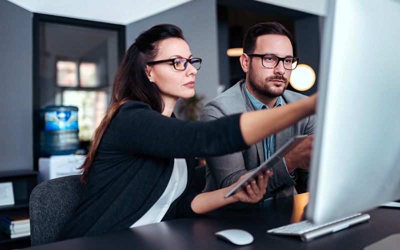 Two business professionals collaborating on desktop computer 