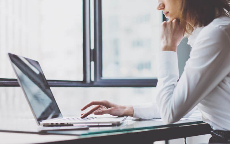 Business professional on laptop computer in front of windows