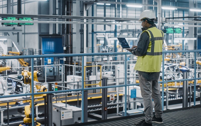 Man in hard hat on laptop in warehouse