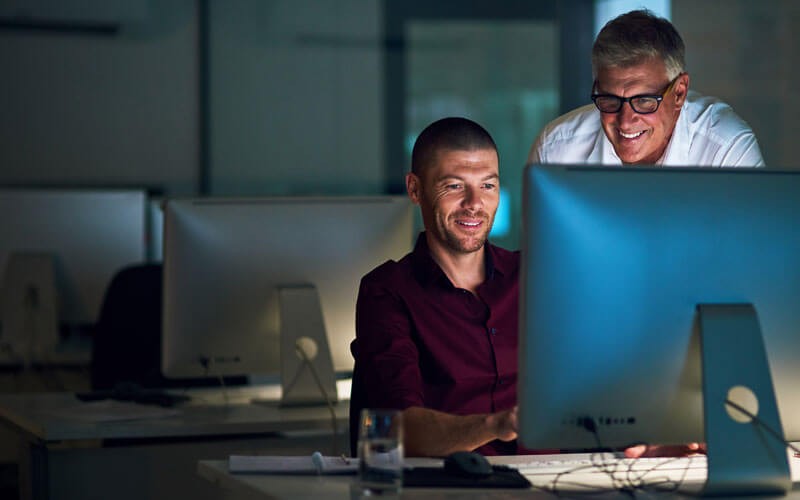 Two men smiling at monitor 