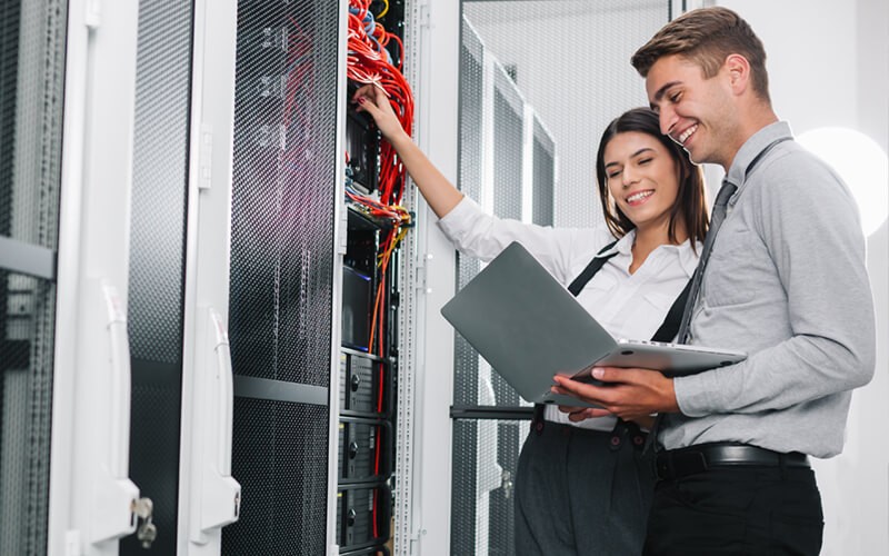 Two IT engineers work in data center with laptop computer