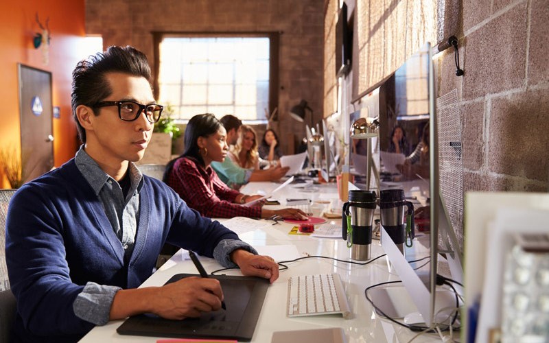 Designer using tablet to design on desktop