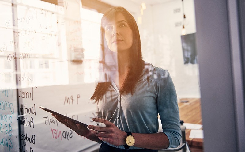 Female thinking in front of white board