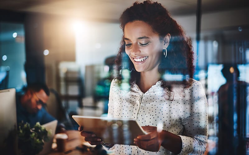 Smiling businesswoman on tablet in office at night