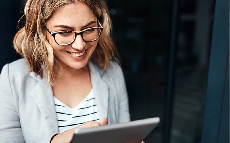 Smiling business woman on tablet outside
