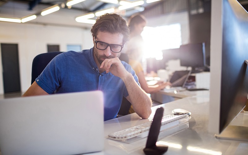 Serious businessman looking at software investments on laptop computer